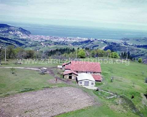 Vista aérea de un caserio de Zarautz con el pueblo al fondo.