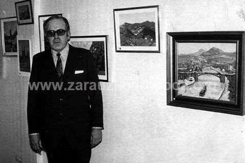 Fotografía del pintor Juan Luis Mendizabal ante varios de sus cuadros