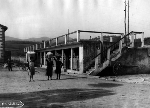 Mujeres con baldes de ropa en la cabeza en el exterior del lavadero de Zarautz